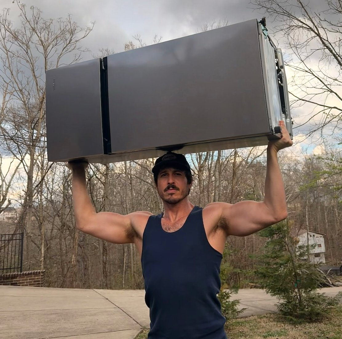 Morgan Evans lifts a refrigerator over his head in an Instagram post.
